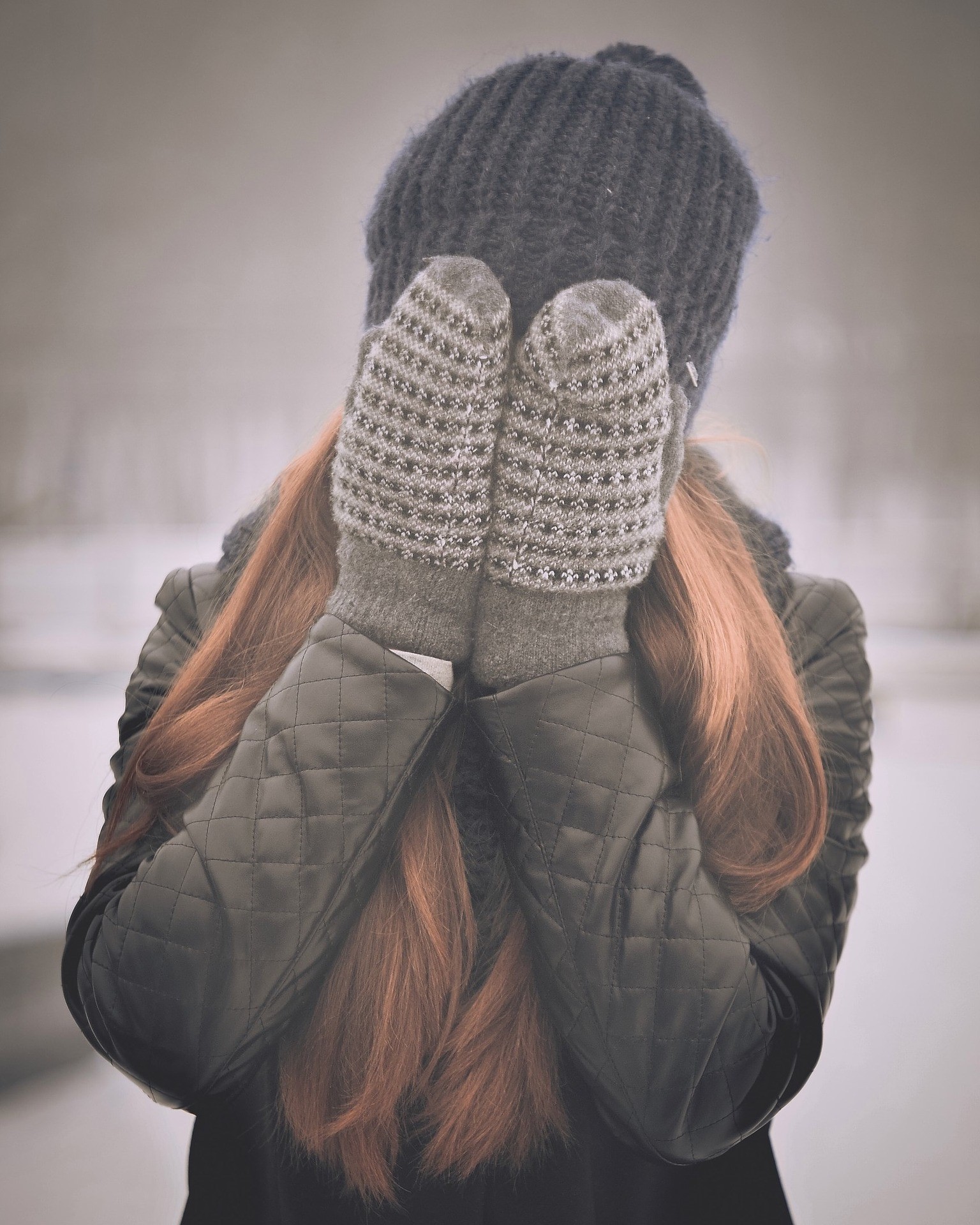 woman covering her face with gloves in a snowy forest