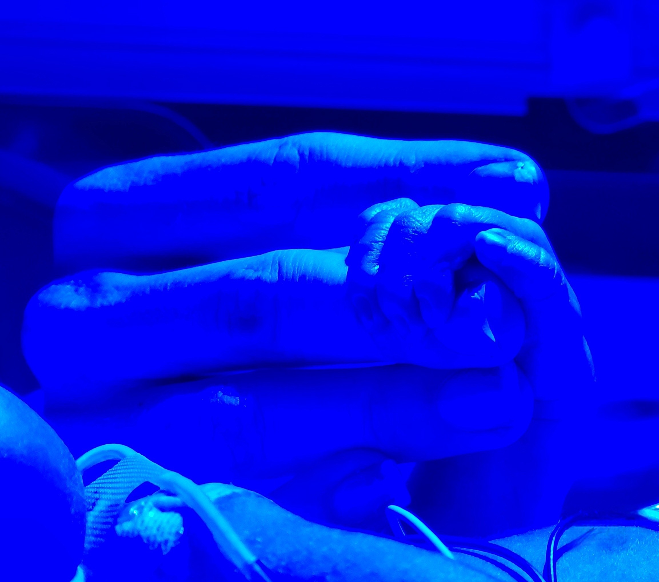 Newborn holds his mom's finger in the NICU 